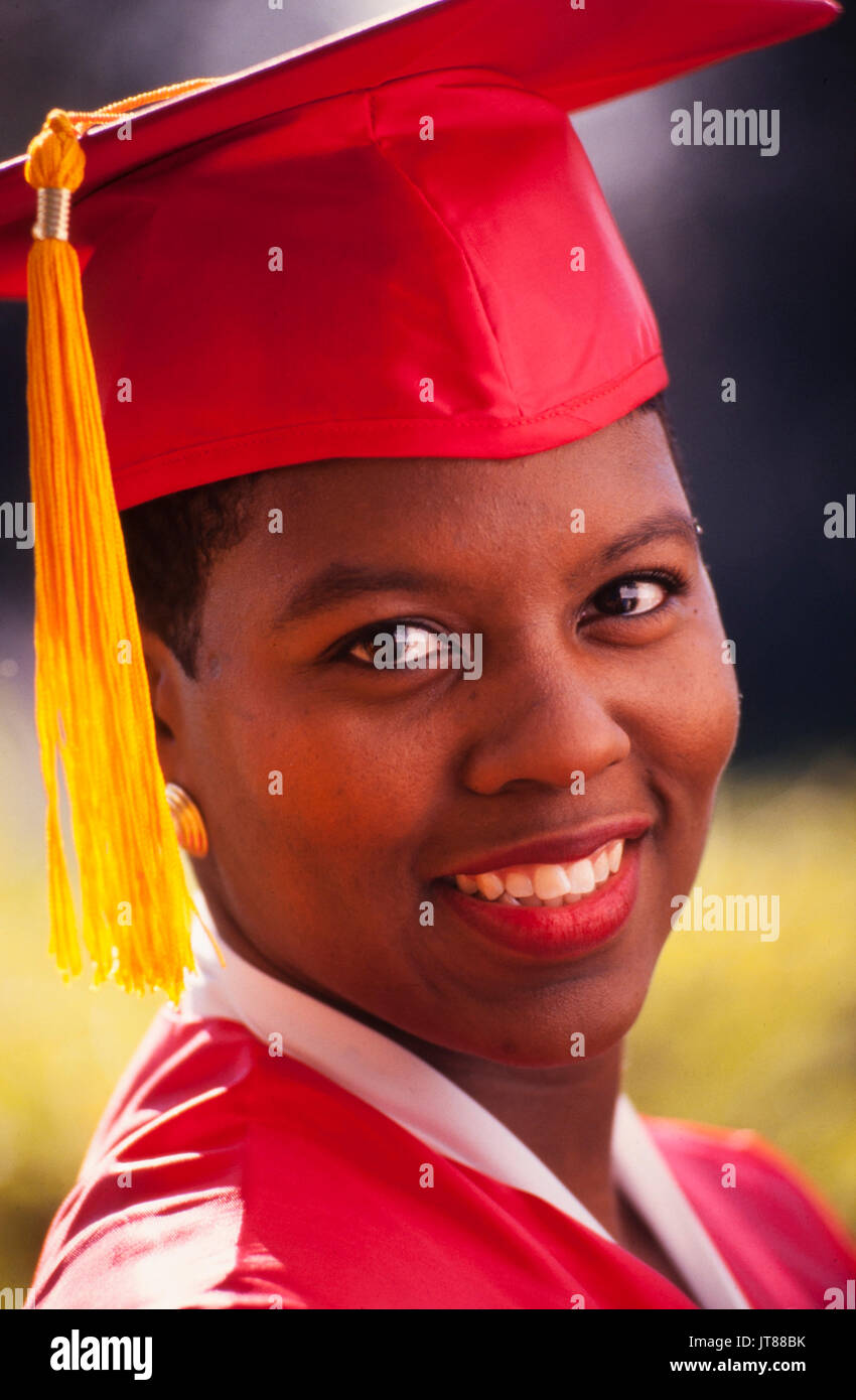 An African American graduate in her red cap and gown with a gold tassel. Stock Photo