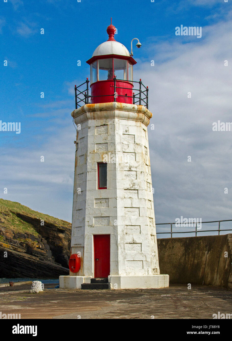 19th century red and white lighthouse, now disused, beside harbour wall at village of Lybster, Scotland Stock Photo
