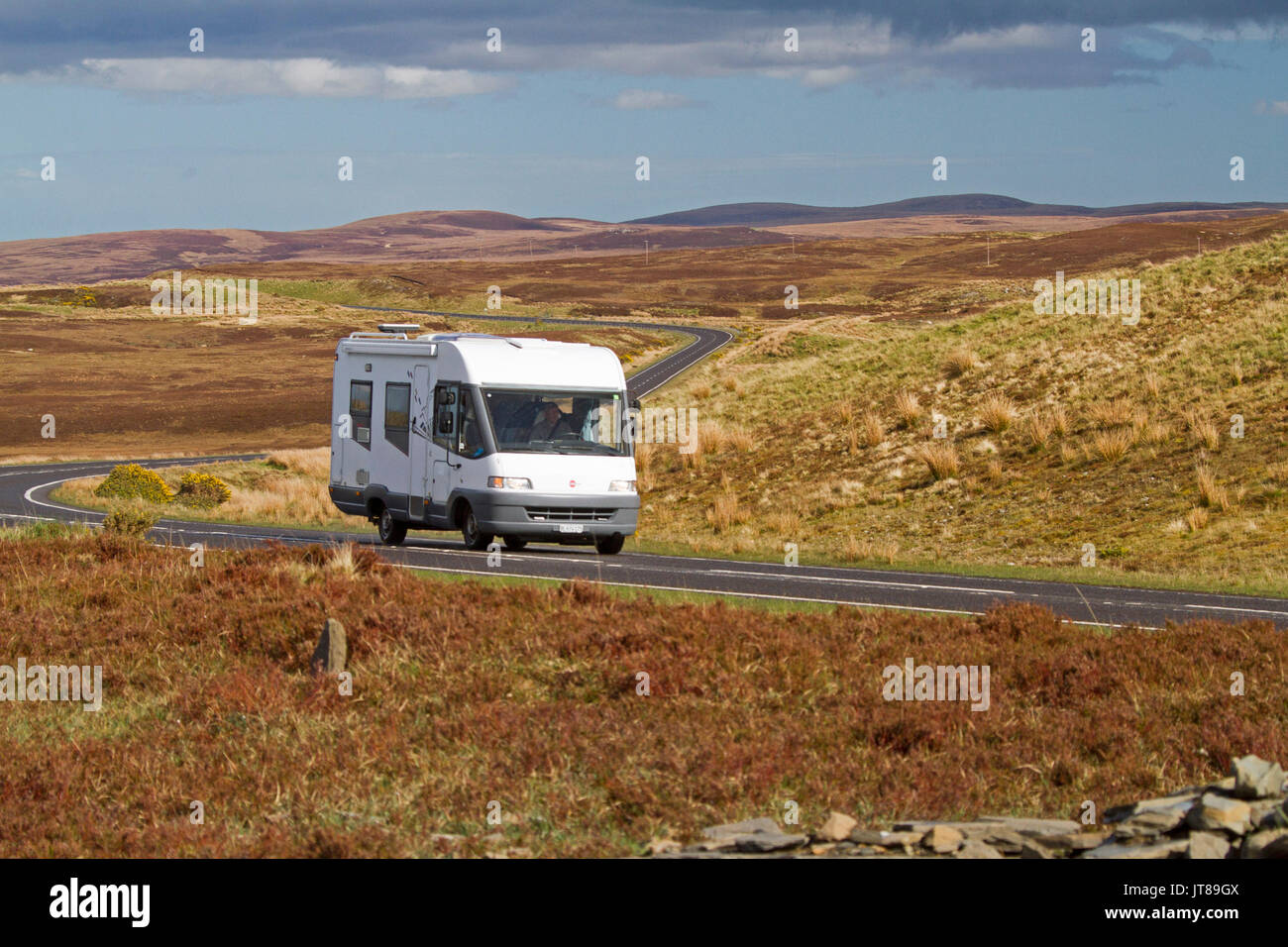 Motorhome on road slicing across vast and spectacular landscape of golden grasses and heather in Scottish highlands Stock Photo