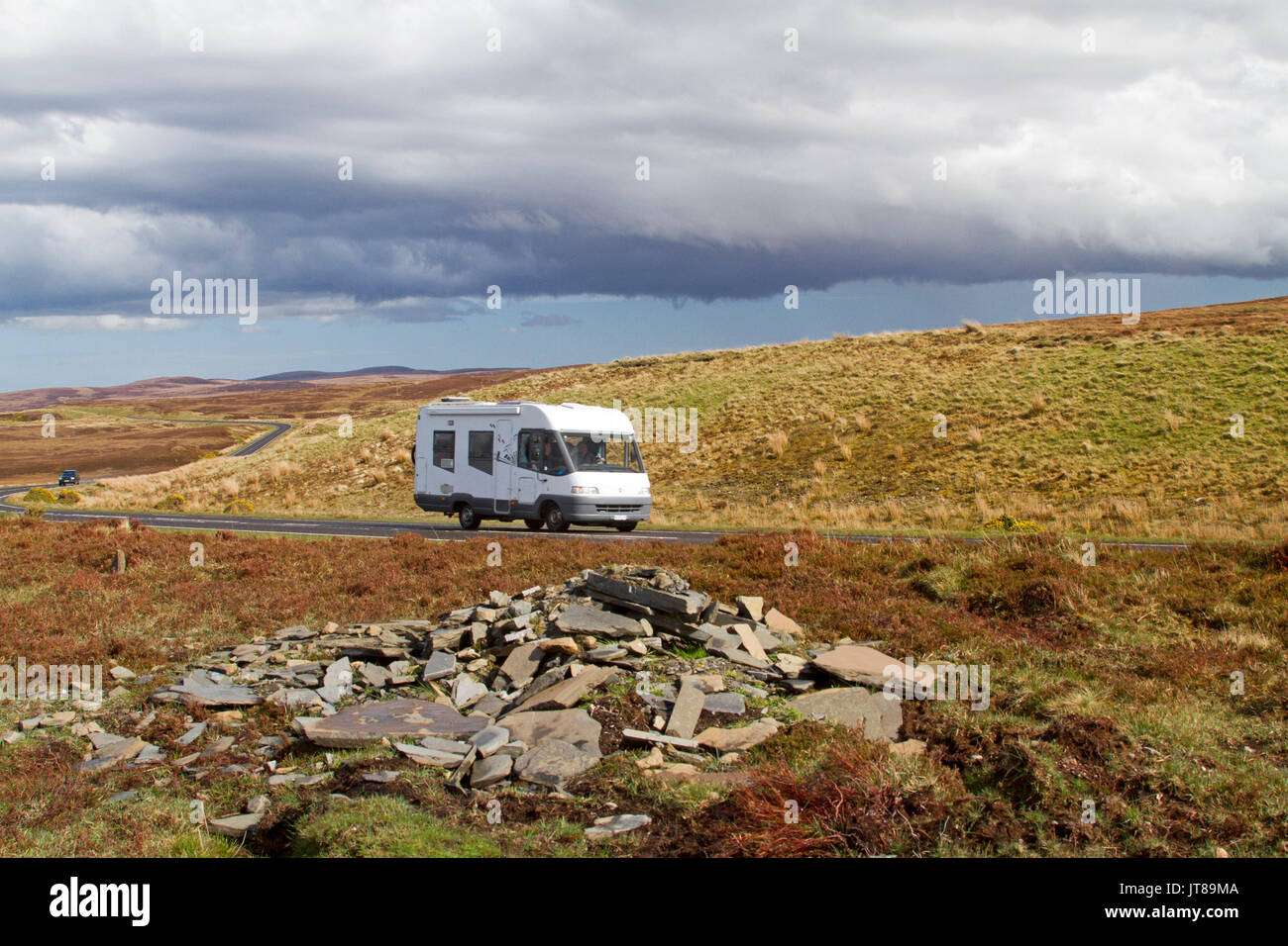 Motorhome on road slicing across vast and spectacular landscape of golden grasses and heather in Scottish highlands Stock Photo