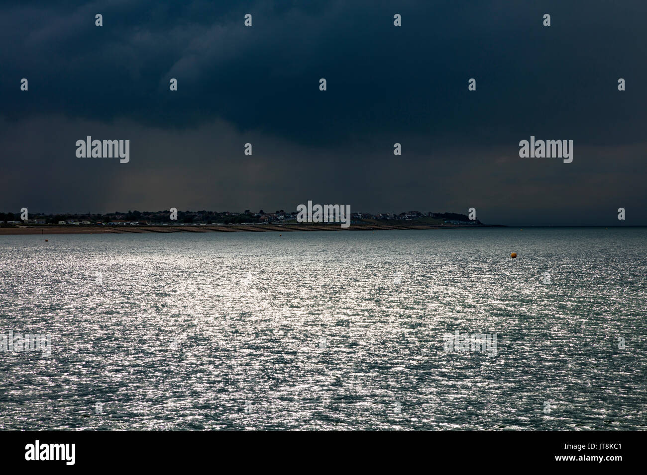 Herne Bay, Kent, UK, 8th August 2017. UK Weather News. A drizzily summers day at Hampton Herne Bay, ends with dark clouds and thunderstorms appearing over the Thames Estuary with a view towards Tankerton and the Swale Estuary. Some sun breaks through the dark clouds. Credit: Richard Donovan/Alamy Live News Stock Photo