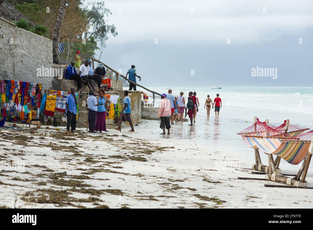 Locals wait by their stalls ib the beach to sell goods to tourists walking by at the nearby resort, Diani, Kenya Stock Photo