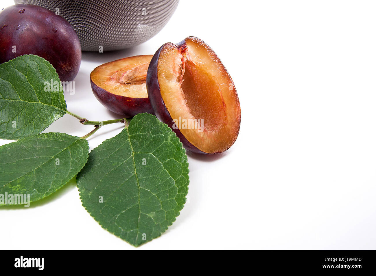 Steel colander with sweet juicy plums, whole and half ripe plums with