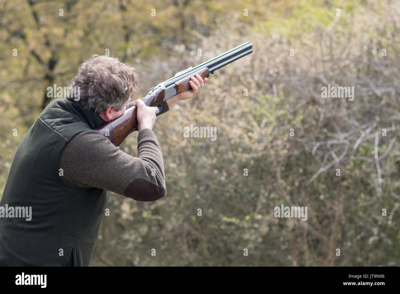 Hunter in forest during hunting season aiming before shoot Stock Photo
