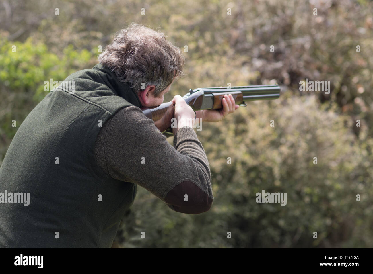 Hunter in forest during hunting season aiming before shoot Stock Photo