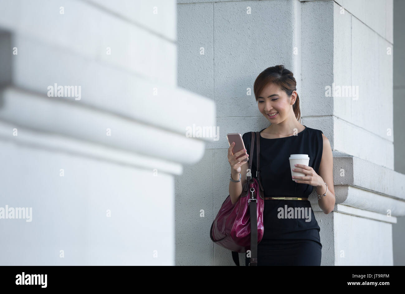 Portrait of an Chinese businesswoman standing outside using her smart phone. Stock Photo