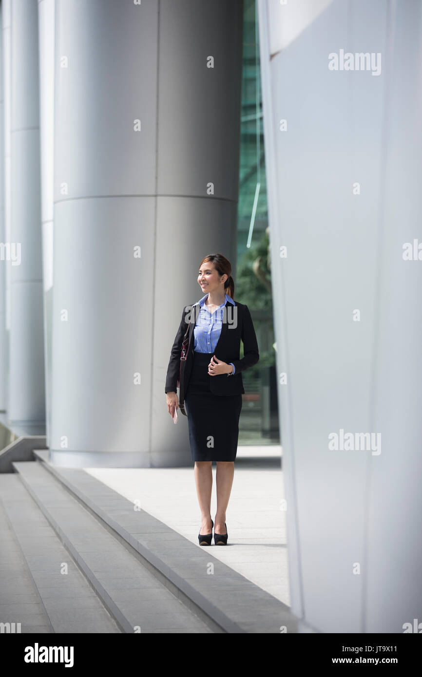 Asian business woman standing outside with office buildings in the background. Portrait of a Chinese business woman looking at the camera. Stock Photo