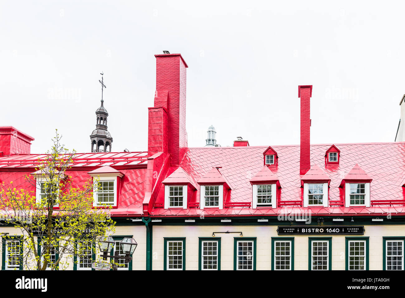 Quebec City, Canada - May 29, 2017: Old town Sainte Anne street with red restaurant bistro roof and Notre-Dame church steeple Stock Photo