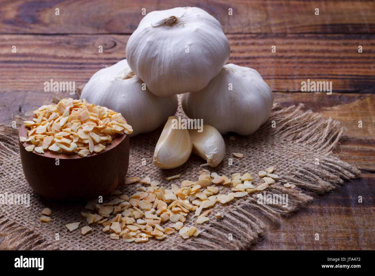 garlic cloves, bulb and flakes on old wooden board Stock Photo