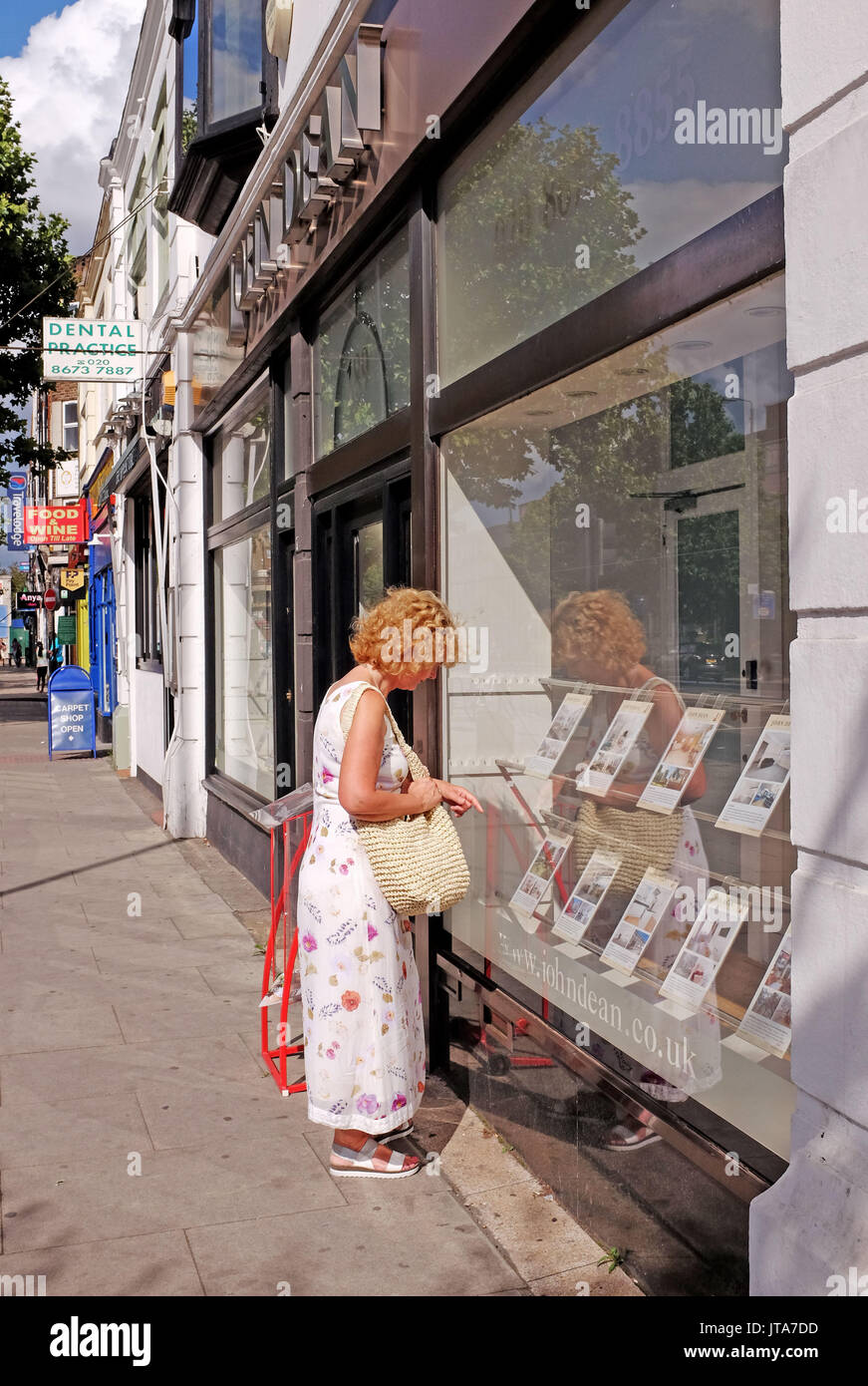 London UK - Woman looking in a Balham Estate Agents window South London house and flat prices Stock Photo