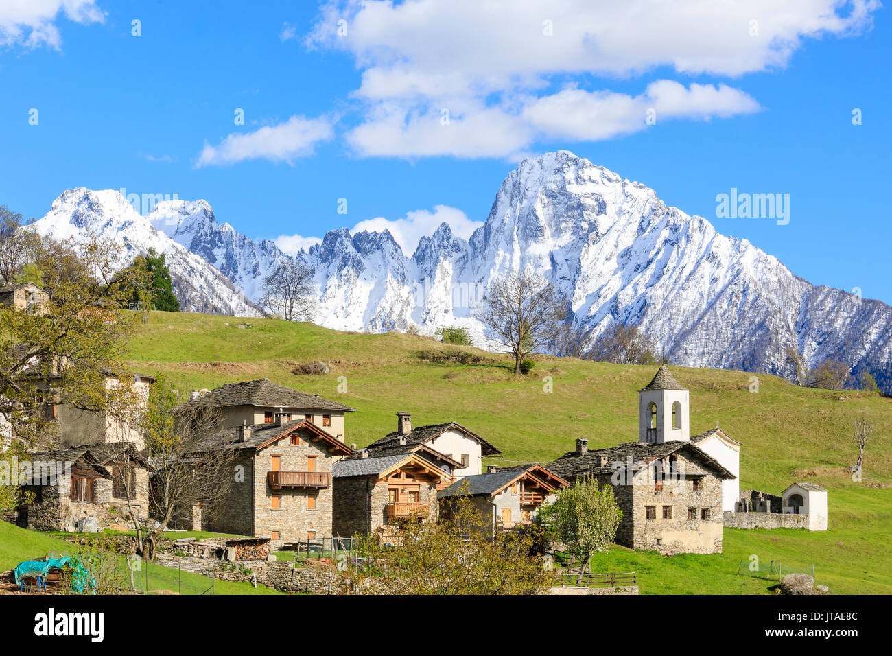Alpine village and meadows framed by the snowy peak of Pizzo di Prata, Daloo, Chiavenna Valley, Valtellina, Lombardy, Italy Stock Photo