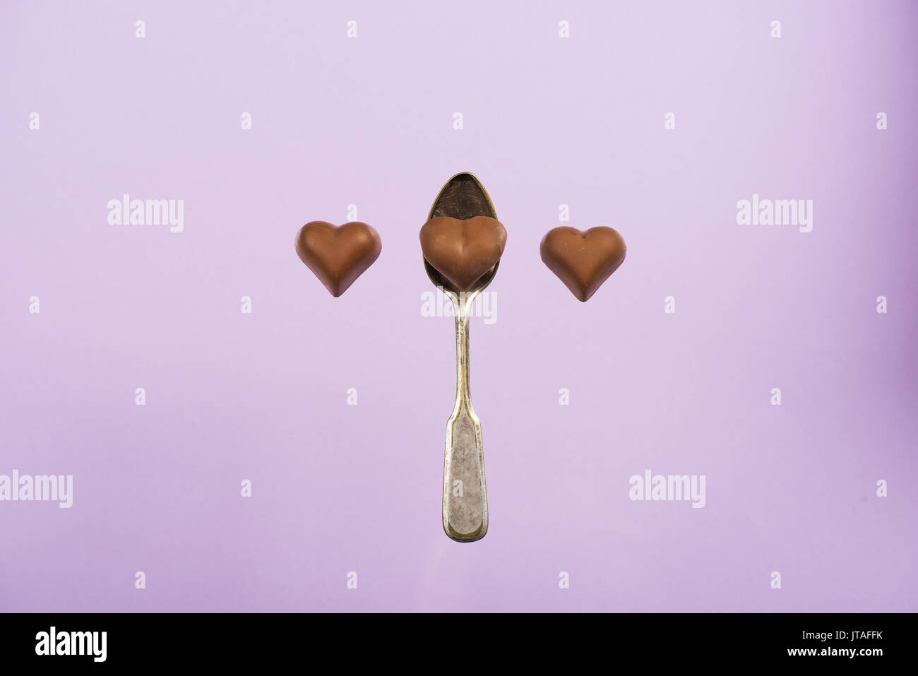 top view of heart shaped chocolate candies and spoon isolated on pink Stock Photo