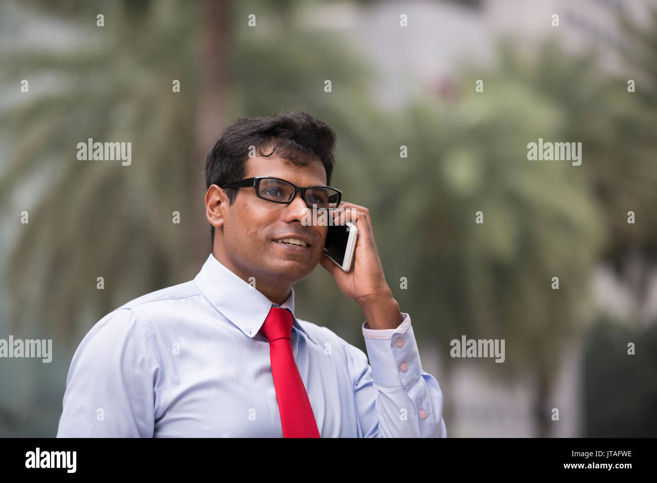 Indian businessman talking on his Smart phone outdoors in Asian city. Stock Photo