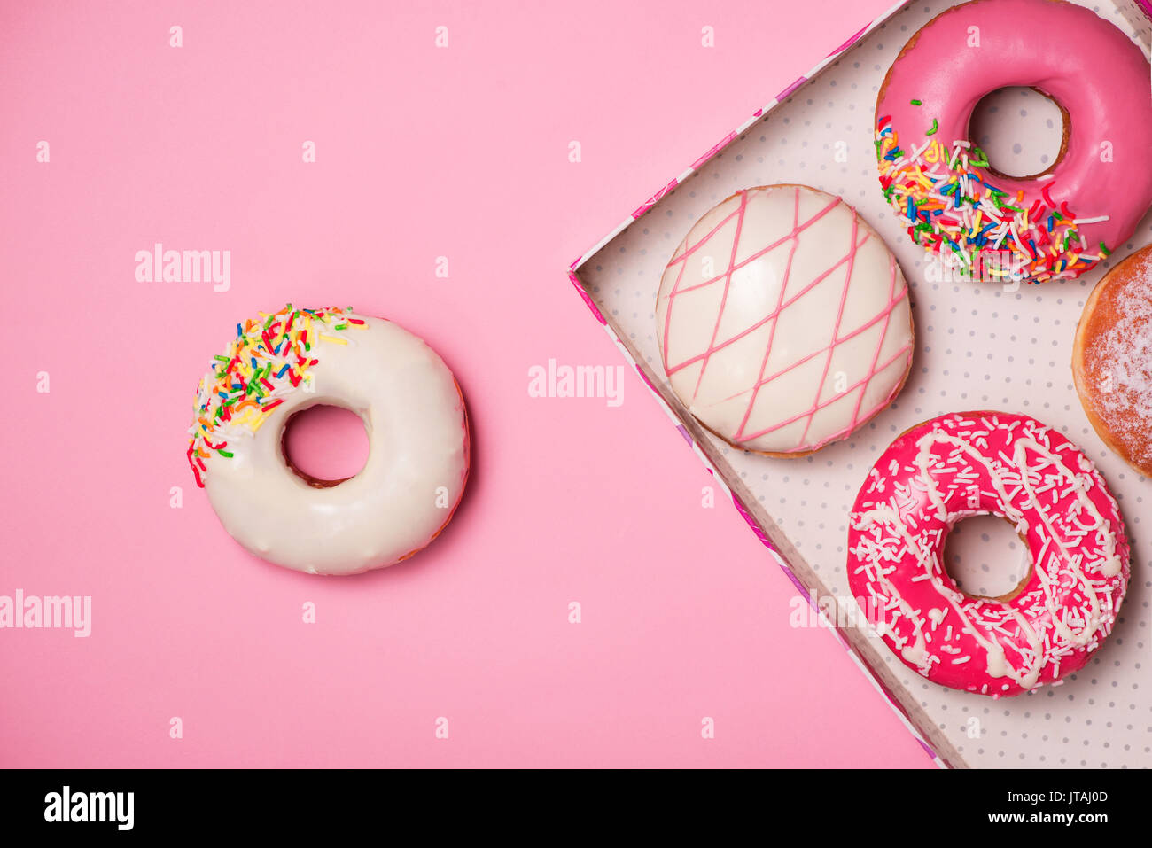 Donuts with icing on pastel pink background. Sweet donuts. Stock Photo