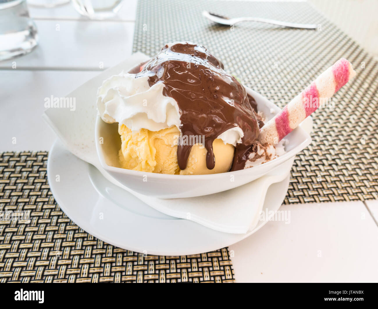 Vanilla ice cream dessert with cream and chocolate and a tube wafer