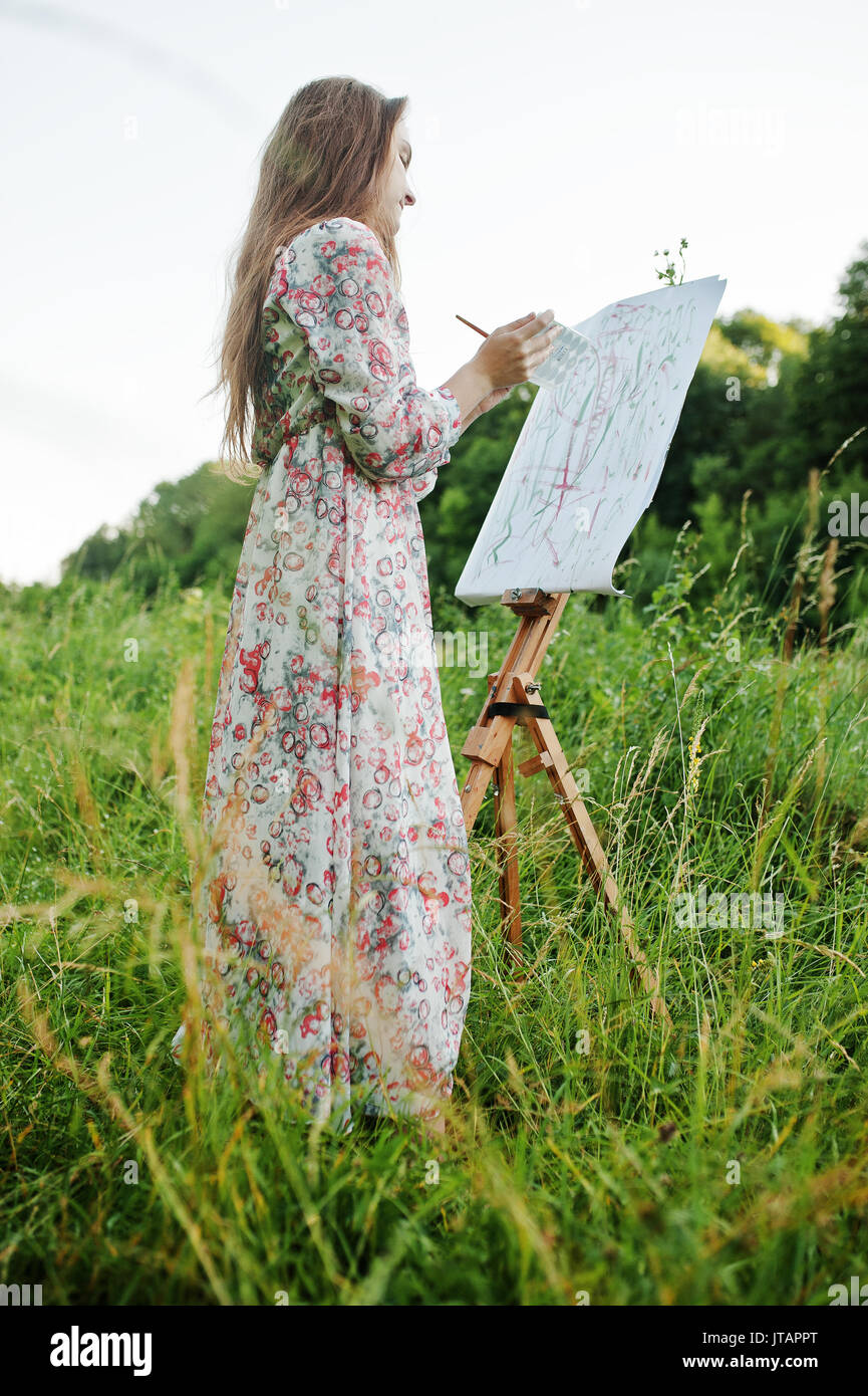 Portrait of an attractive young woman in long dress painting with  watercolor in nature Stock Photo - Alamy