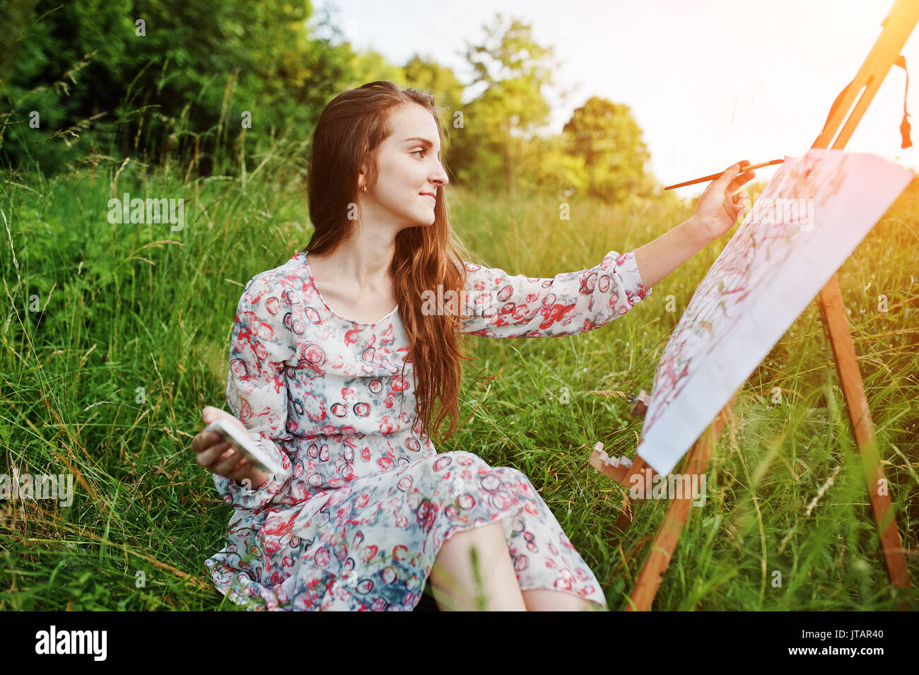 Portrait of a gorgeous happy young woman in beautiful dress sitting on ...
