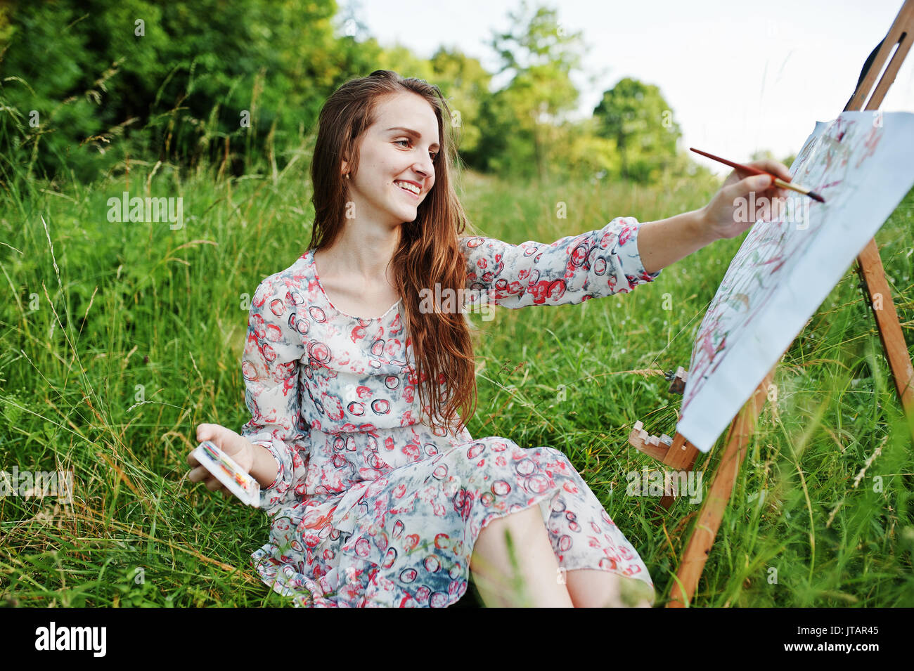 Portrait of a gorgeous happy young woman in beautiful dress sitting on ...