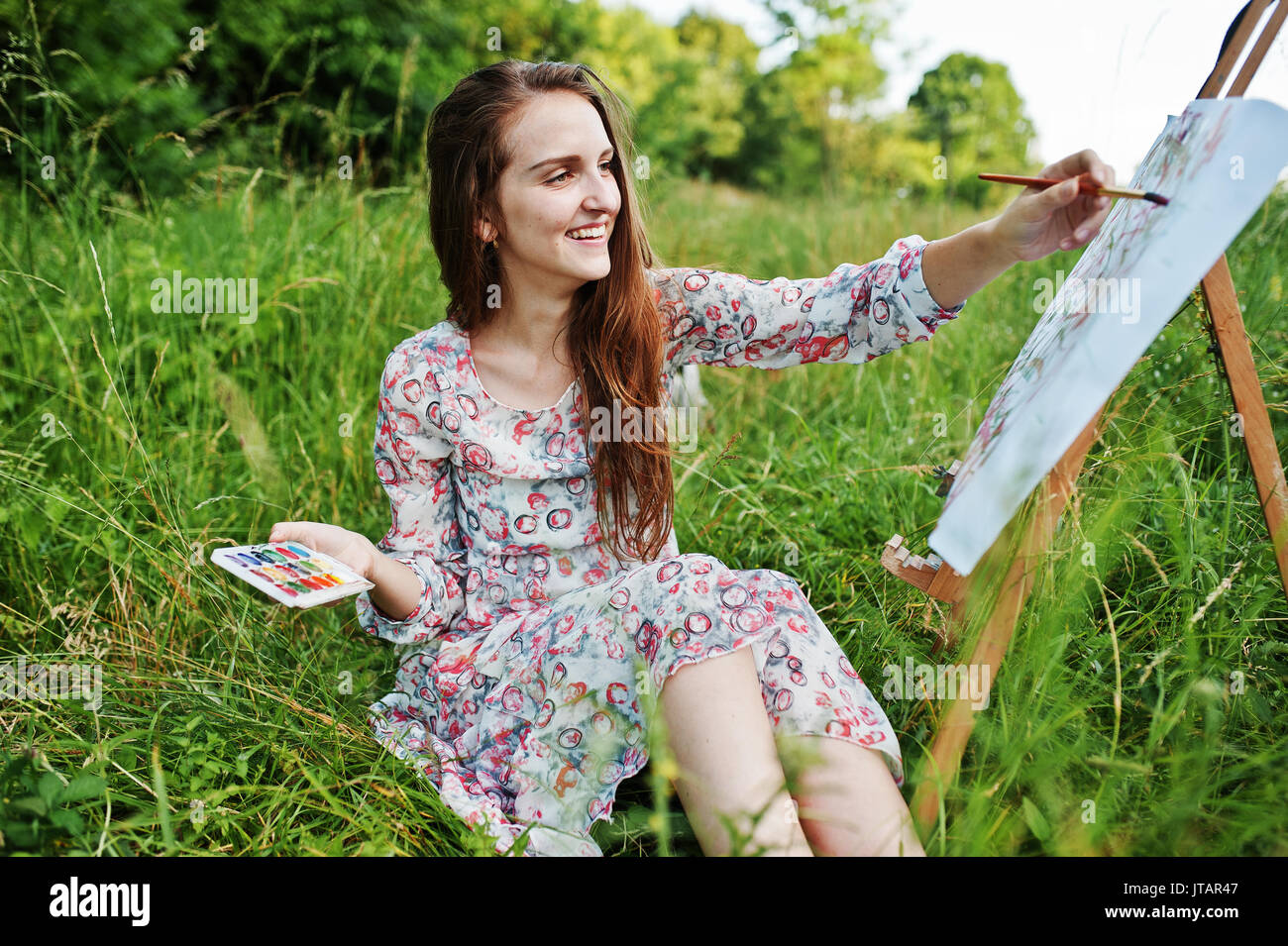Portrait of a gorgeous happy young woman in beautiful dress sitting on ...