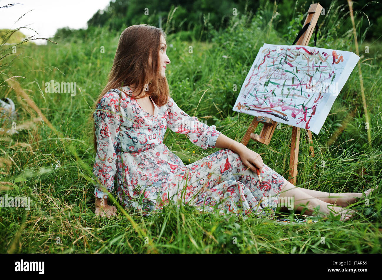 Portrait of a gorgeous happy young woman in beautiful dress sitting on ...