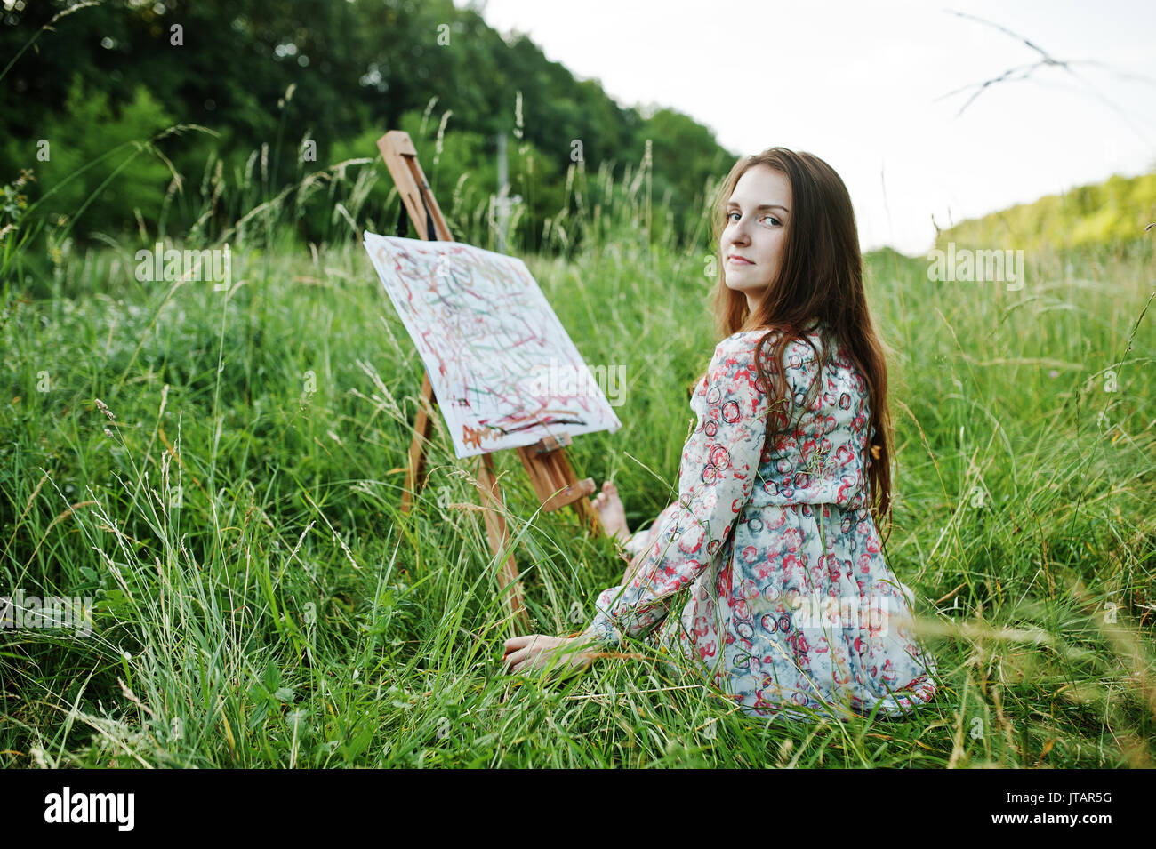 Portrait of a gorgeous happy young woman in beautiful dress sitting on ...
