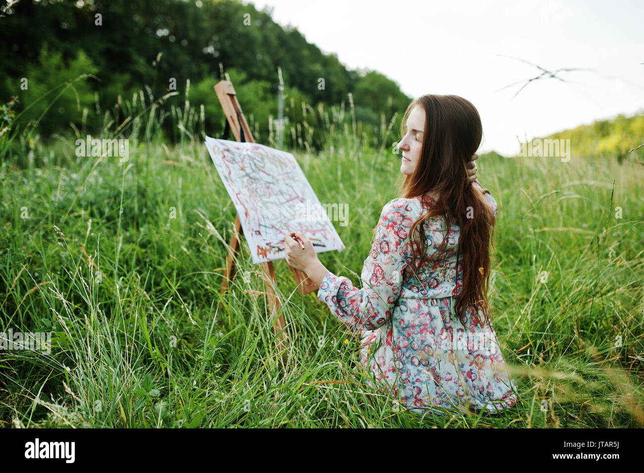 Portrait of a gorgeous happy young woman in beautiful dress sitting on ...