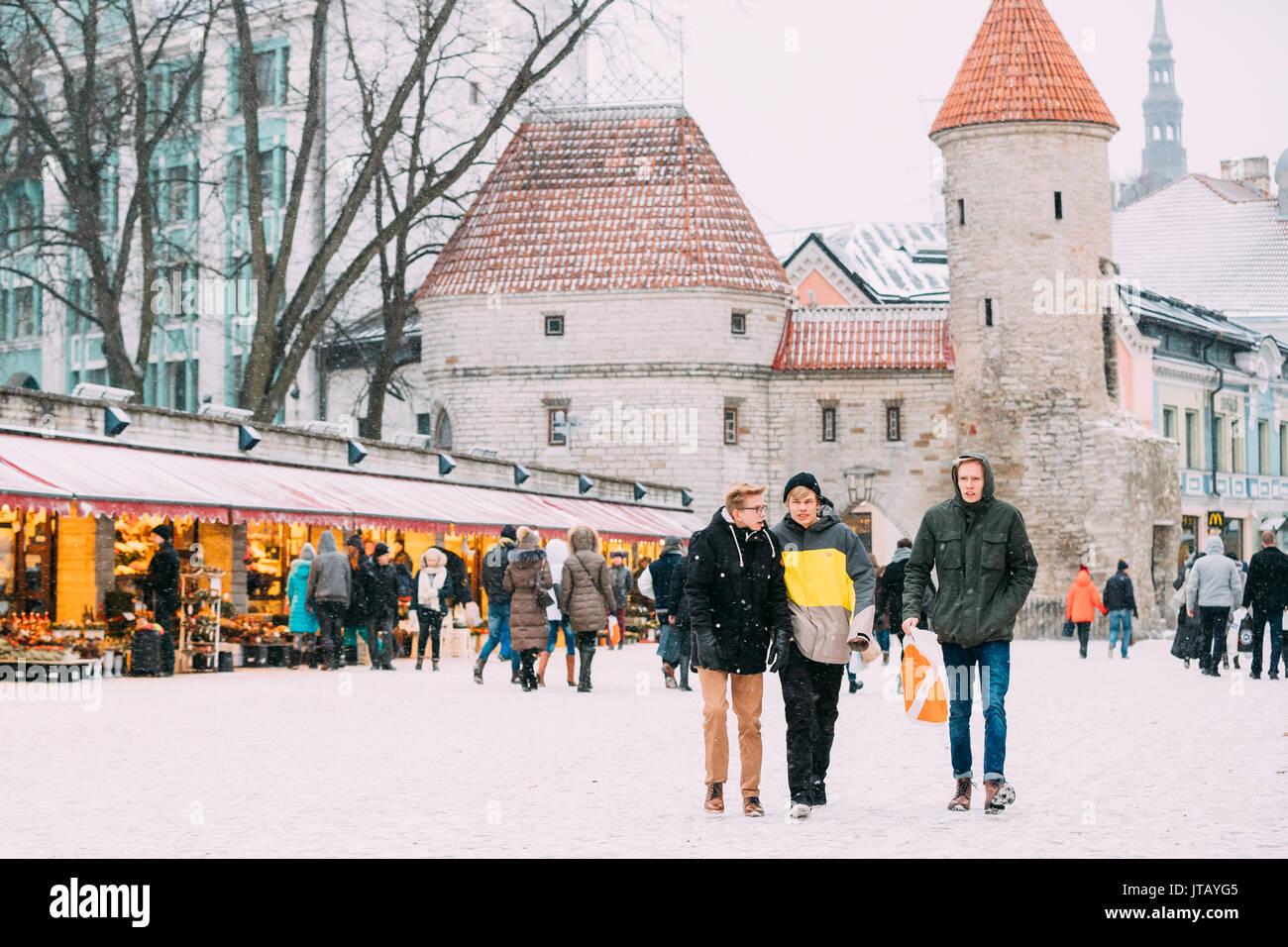 Tallinn, Estonia - December 3, 2016: Young People Walking Near Christmas Xmas Market On Background Of Viru Gate In Winter Snowy Day. Stock Photo