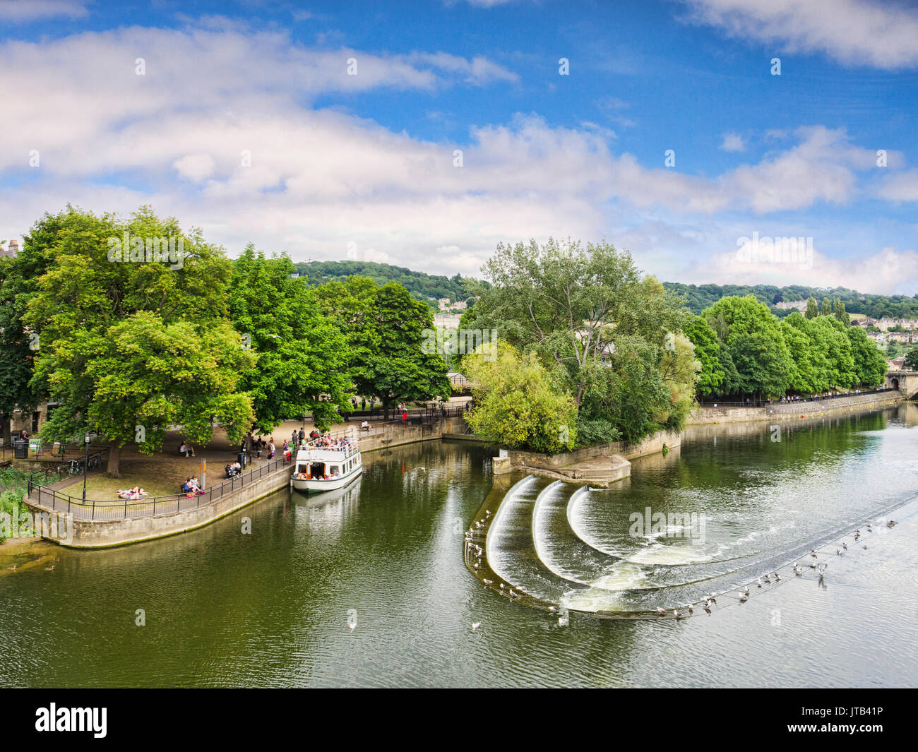 8 July 2017: Bath, Somerset, England, UK - Pulteney Weir, one of the attractions of the city, and a pleasure boat moored nearby. Stock Photo