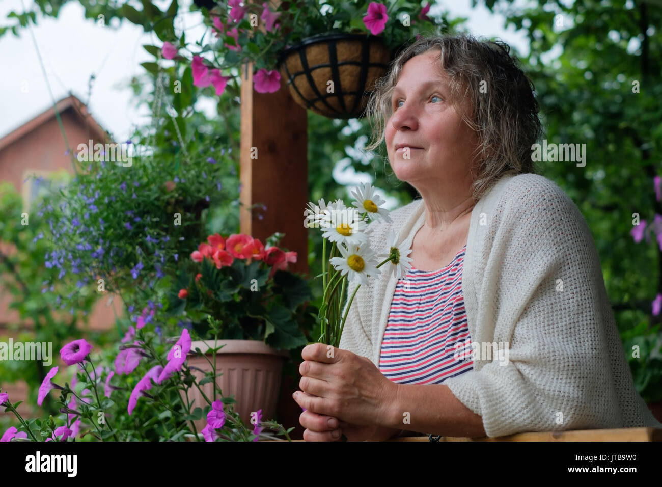 Senior woman in green garden with flowers in hands Stock Photo - Alamy