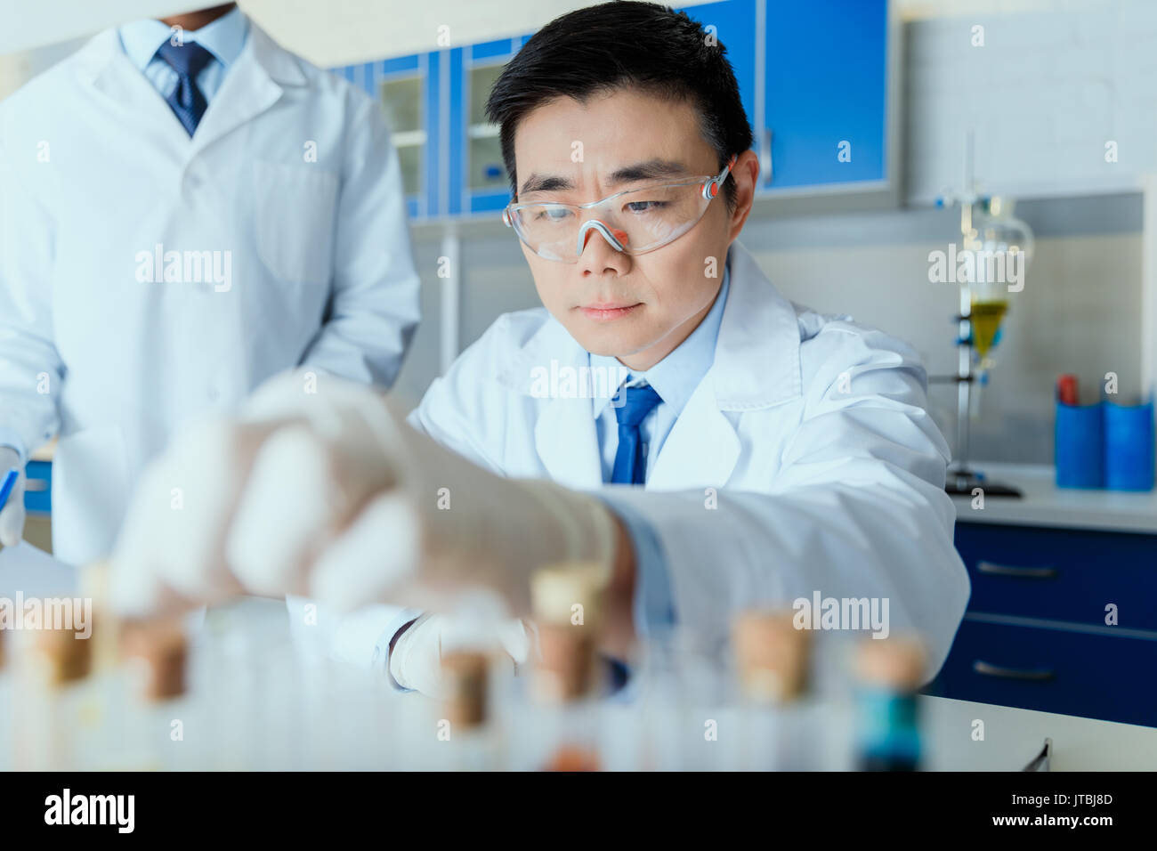 Asian scientist in white coat working in chemical laboratory Stock Photo