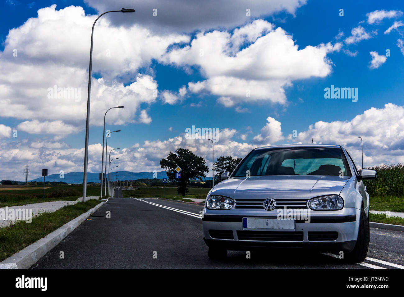 Front of a silver Volkswagen Golf IV parked on the street with beautiful blue cloudy sky in the background. Stock Photo