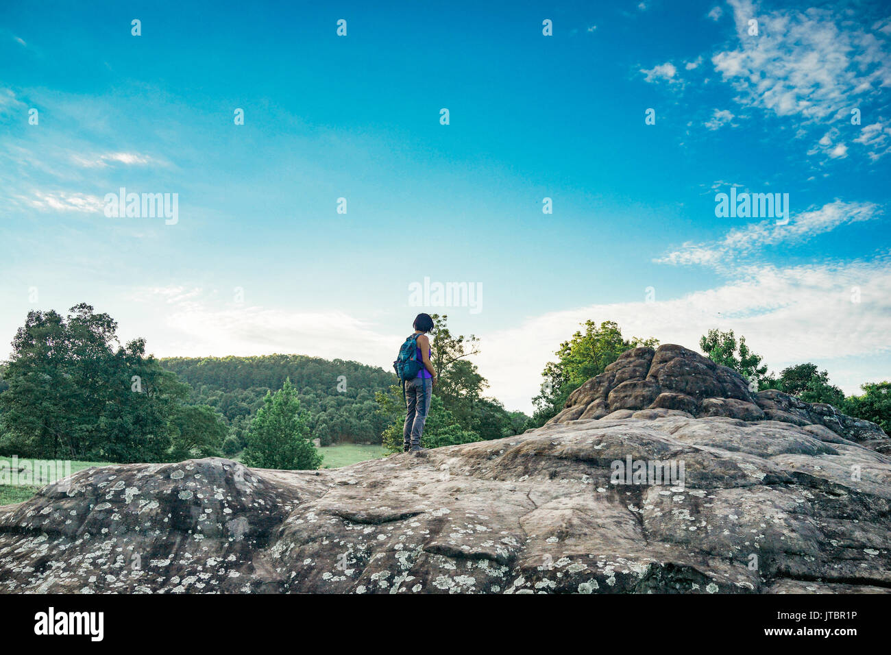 A female hiker stands and looks out in the forrest. Stock Photo