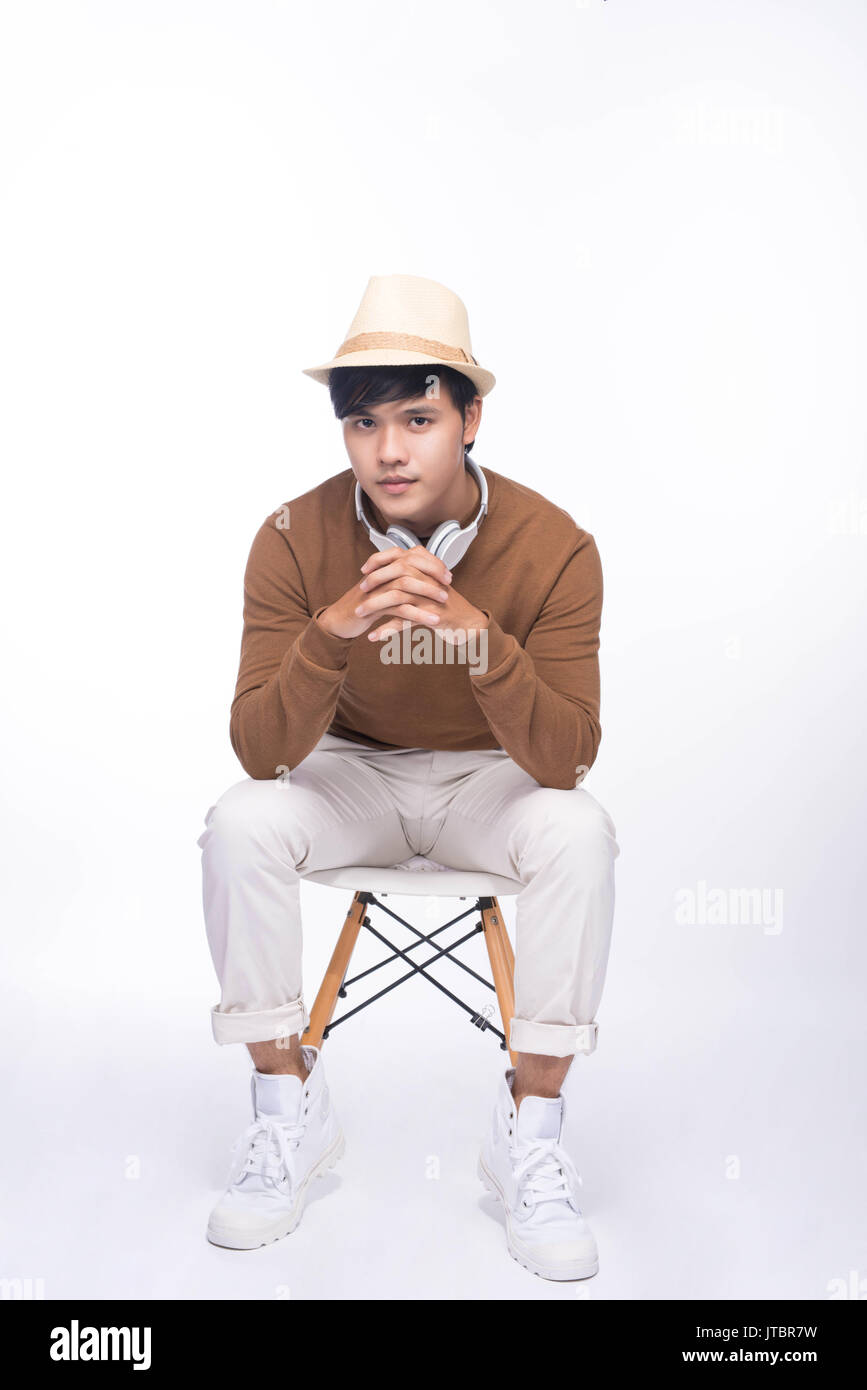 Smart casual asian man seated on chair, in studio background Stock Photo