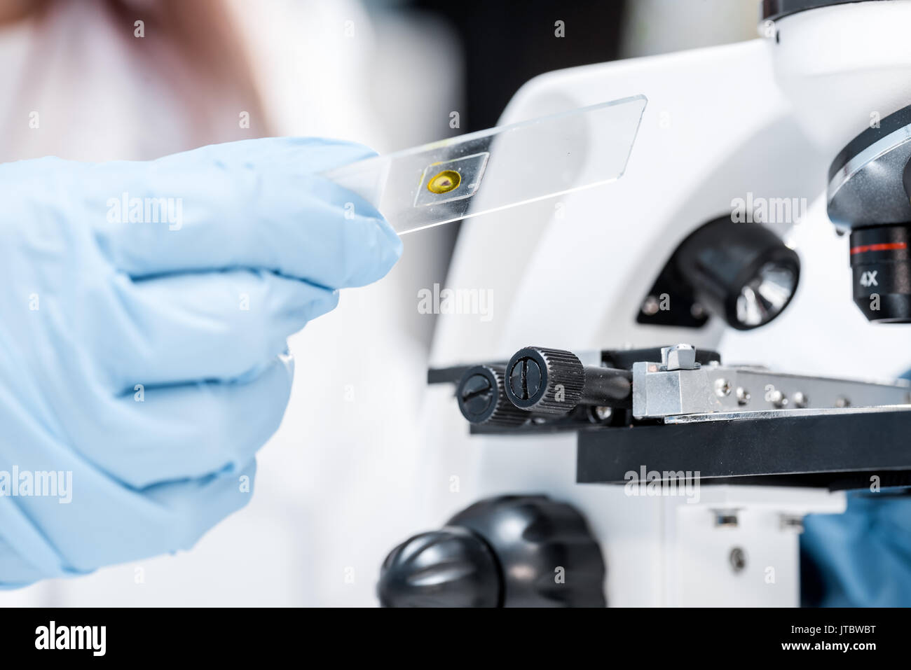 Closeup partial view of scientist holding glass microscope slide while