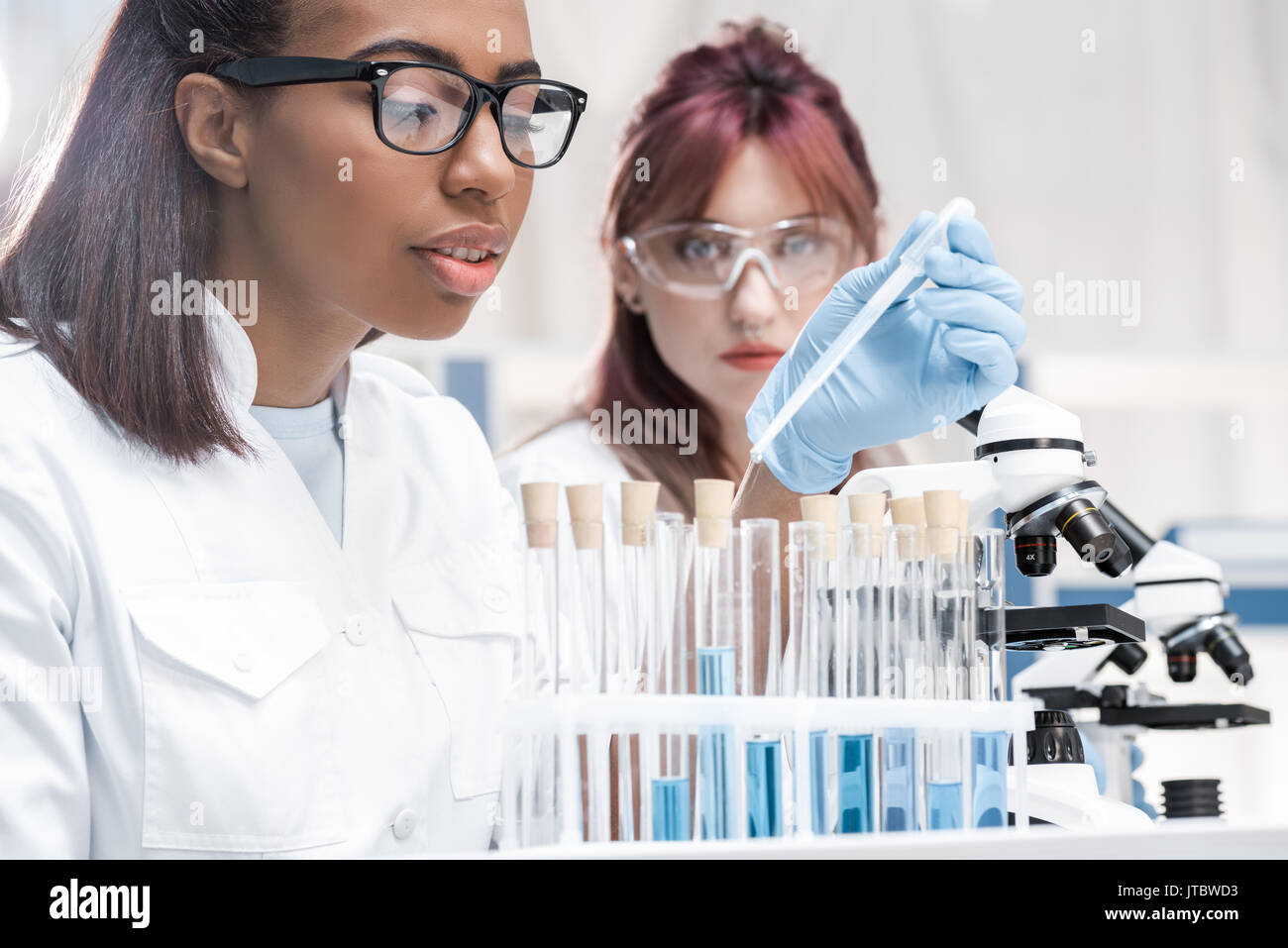 Professional young scientists working with microscope and test tubes in chemical laboratory Stock Photo