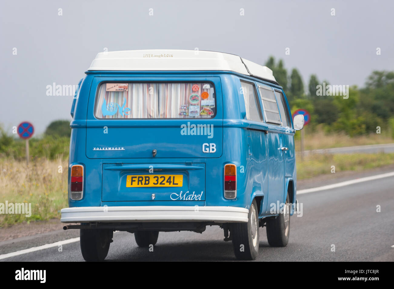 A classic VW campervan driving on a main road in the Uk Stock Photo