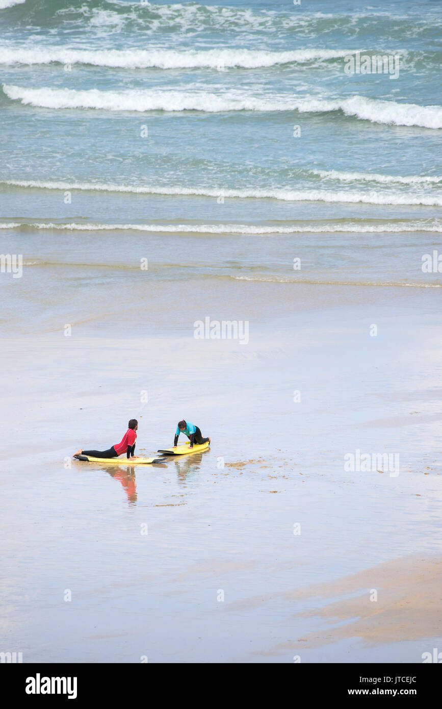 A person learning to surf with a surfing instructor. Stock Photo