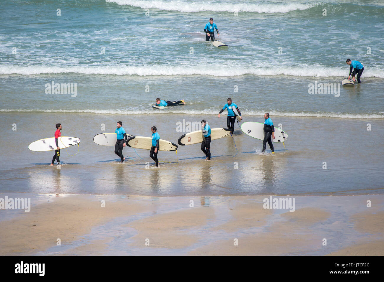 A surf instructor and his students on a beach in Newquay, Cornwall