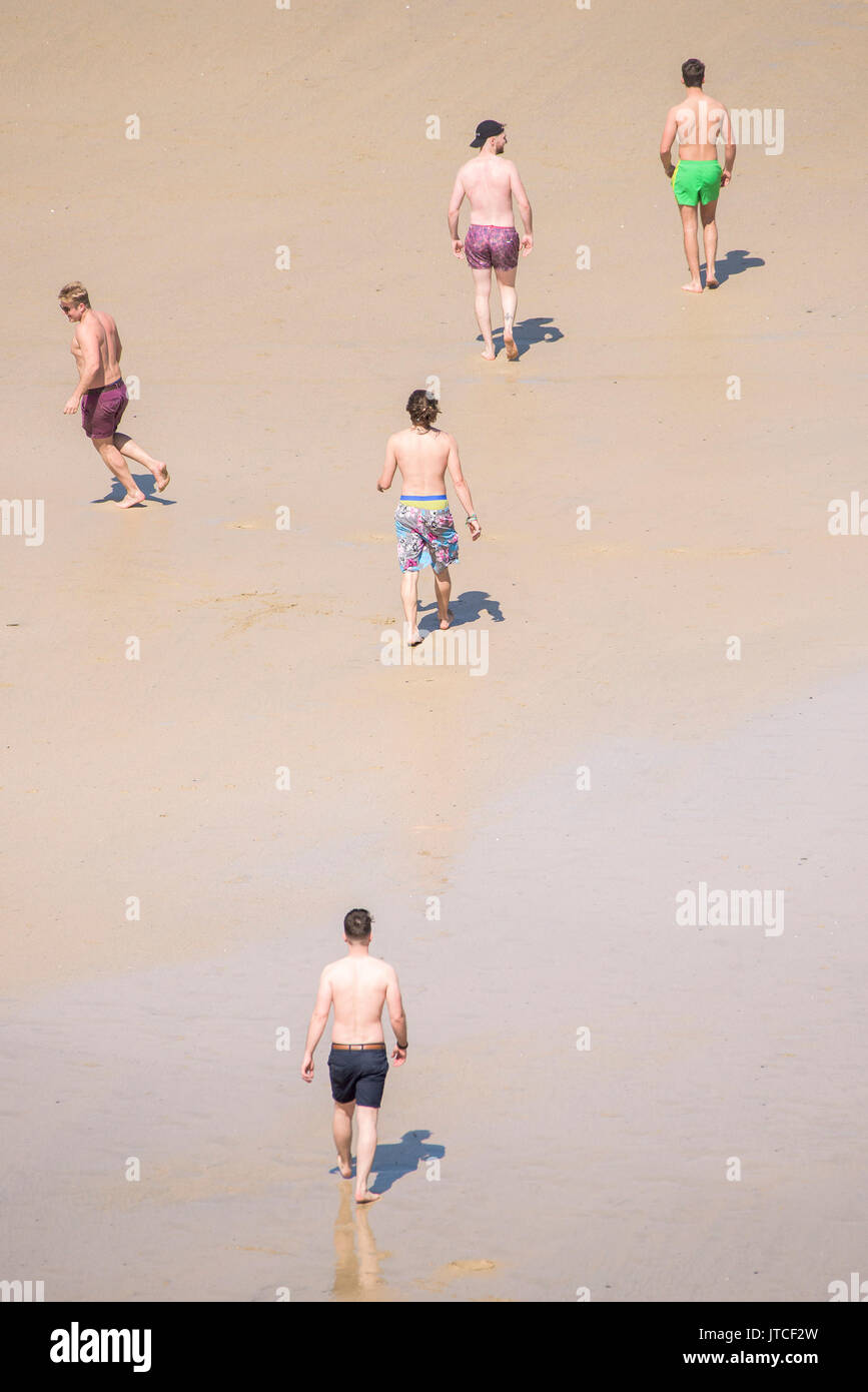 Five young men walking across Great Western Beach in Newquay, Cornwall. Stock Photo
