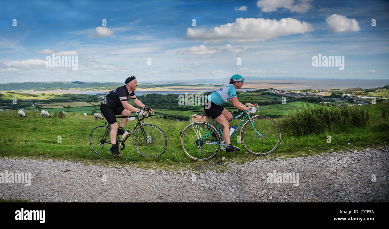 Couple taking part in a vintage cycling event overlooking Morecambe Bay, UK. Stock Photo