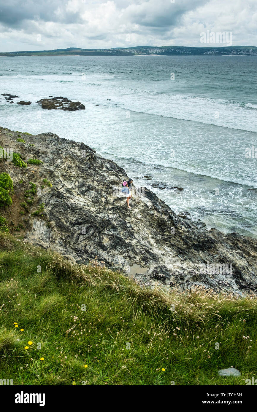 A woman climbing down rocks at Godrevy Beach in Cornwall Stock Photo