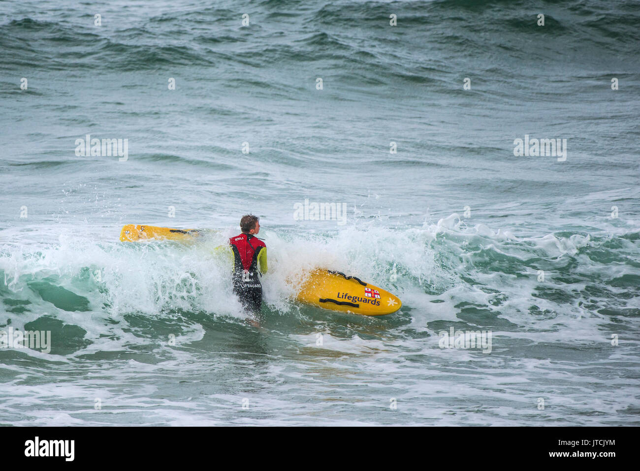 A RNLI lifeguard with his rescue board in the sea. Stock Photo