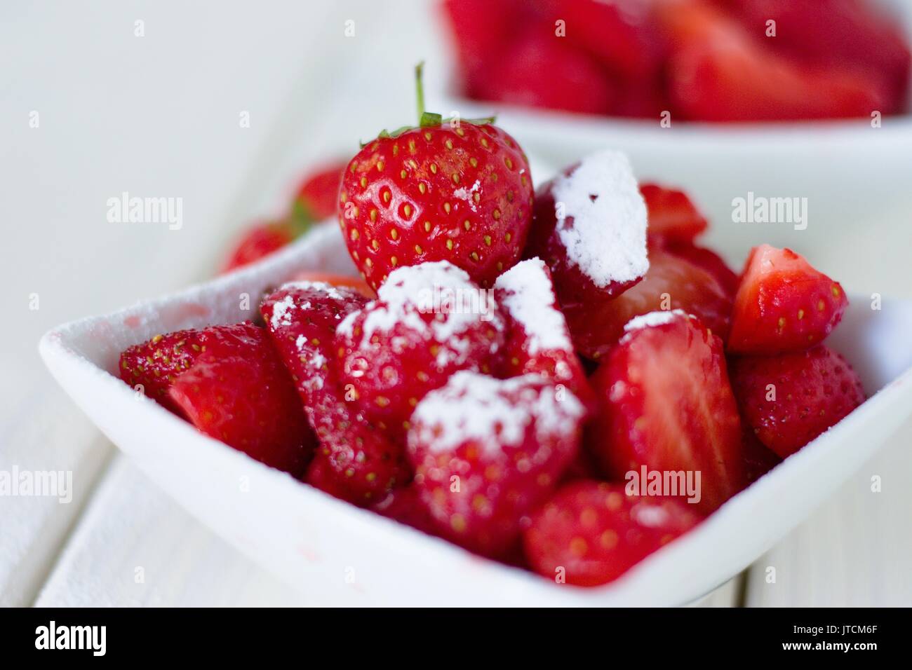 Strawberries with powdered sugar in square bowl.Classic british summer