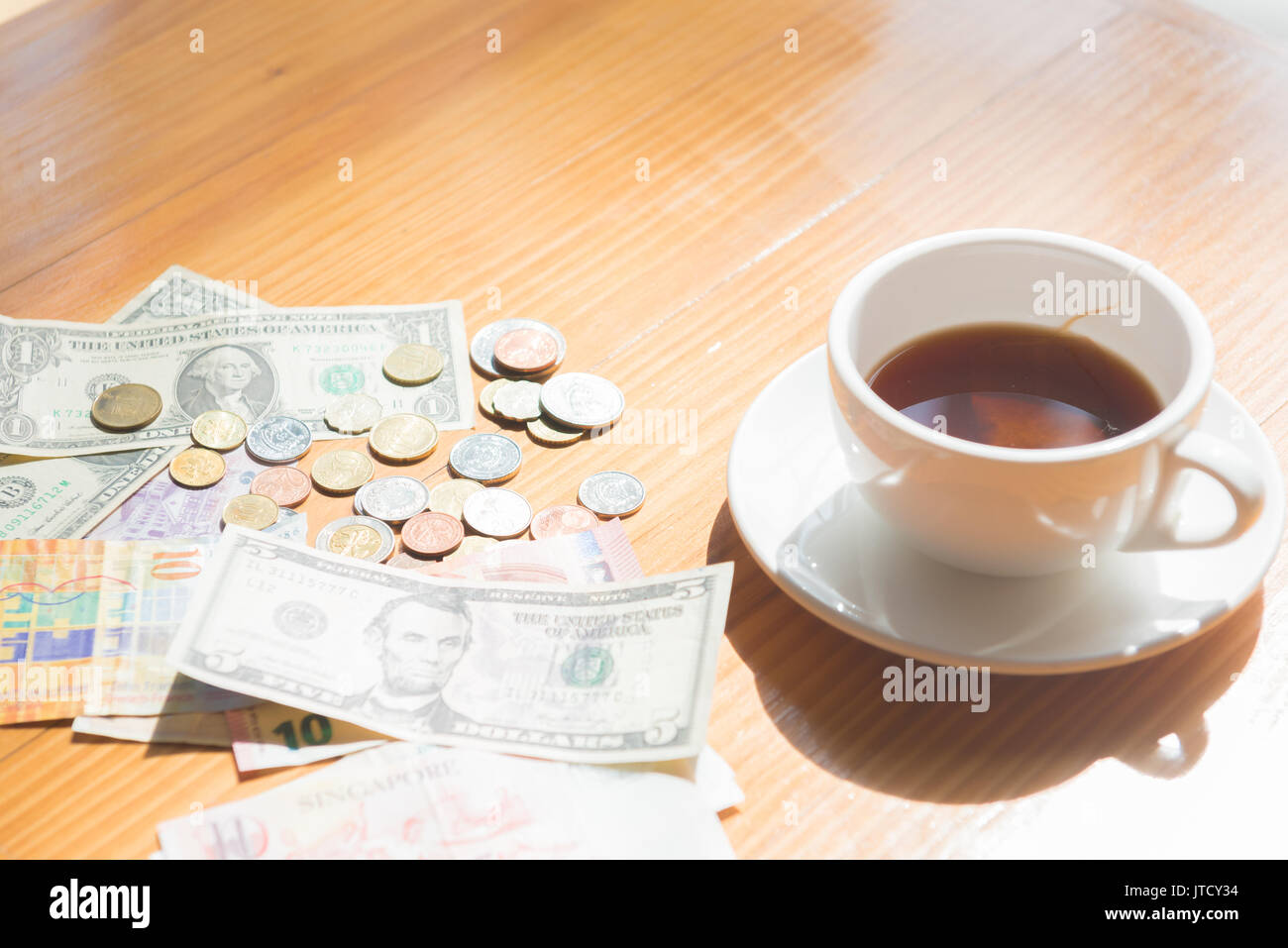 make money tip dollar or euro for travel and tea cup near on the wooden table Stock Photo