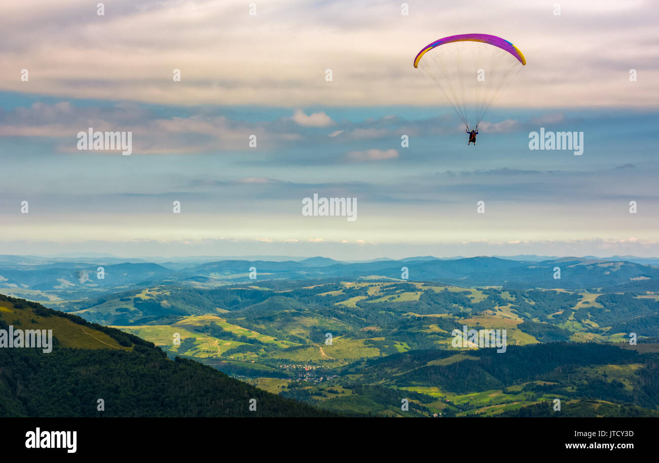 Skydiver flying in the clouds over the rural valley at sunset. parachute extreme sport Stock Photo