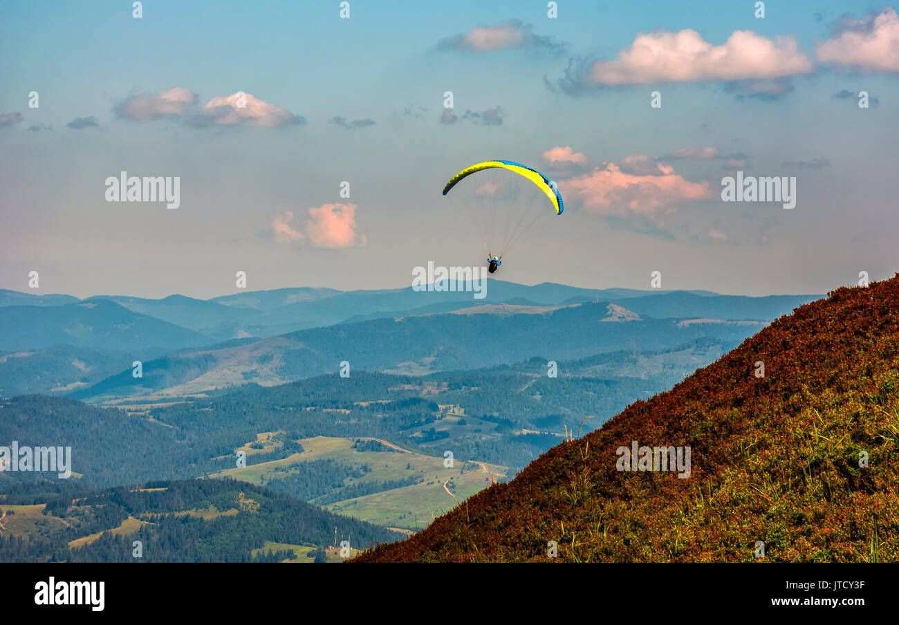 Skydiver flying in the clouds over the countryside valley at sunset. parachute extreme sport Stock Photo