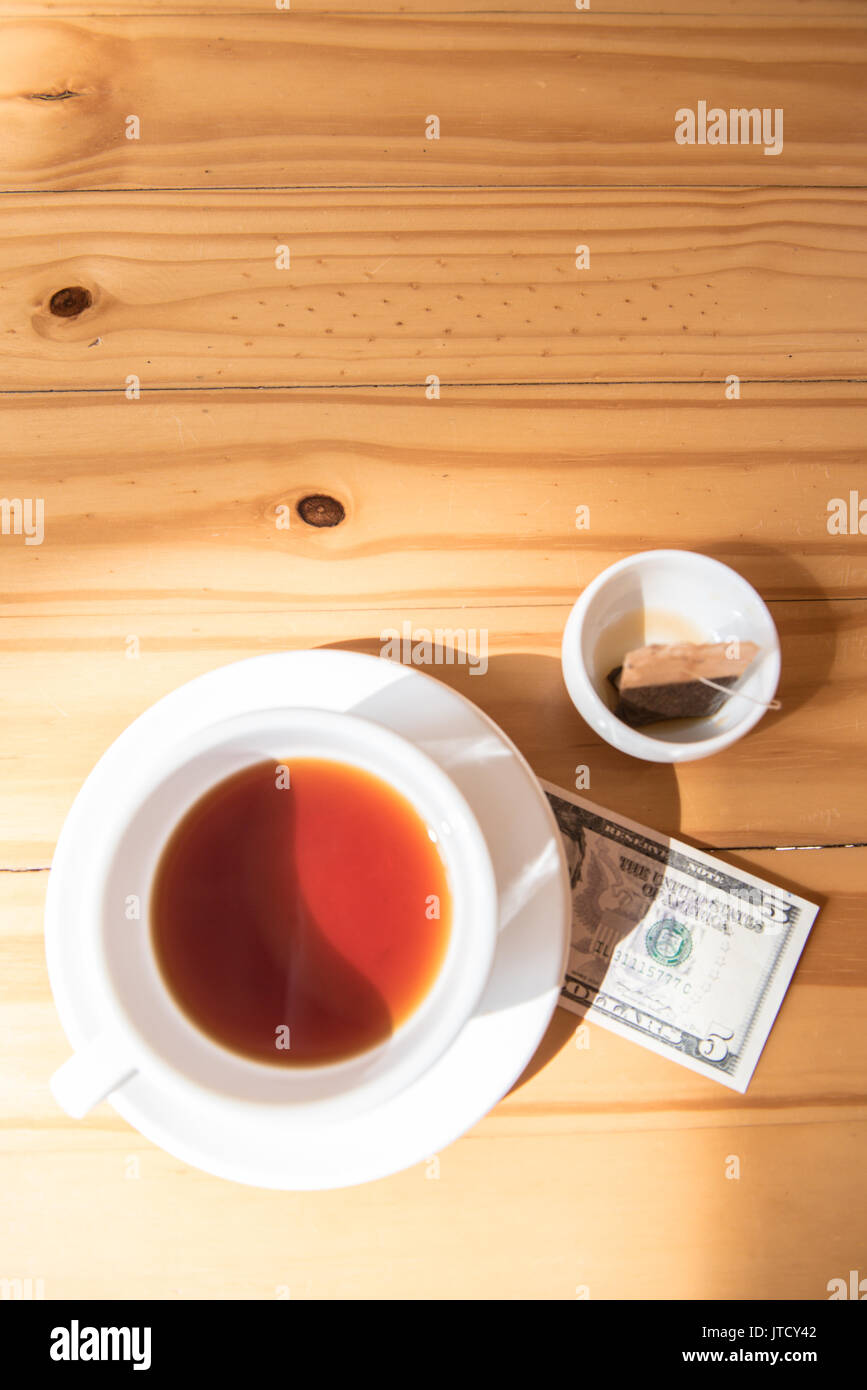 make money tip dollar or euro for travel and tea cup near on the wooden table Stock Photo