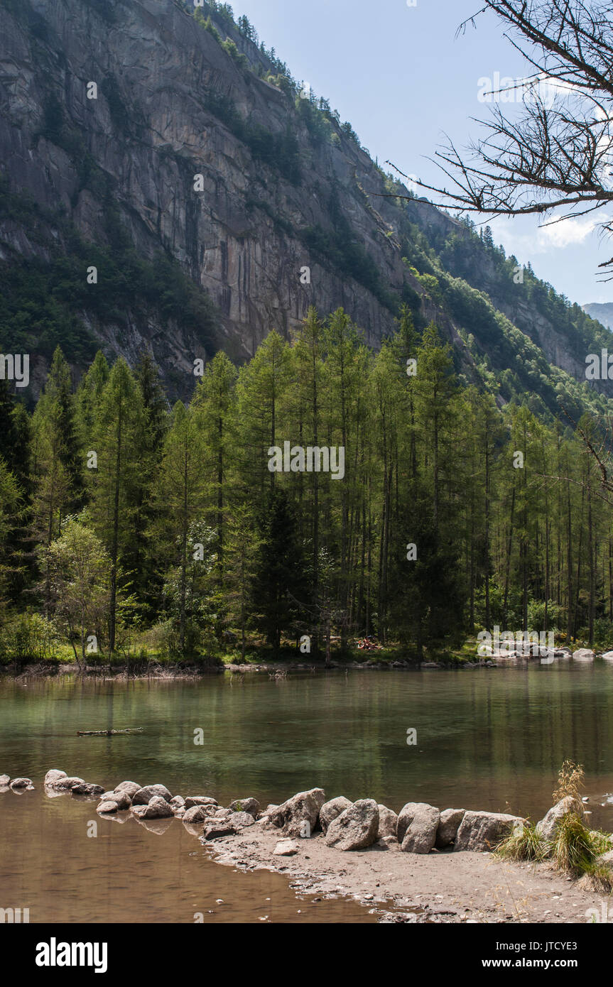 The alpine lake in the Mello Valley, Val di Mello, green valley surrounded by granite mountains and forest trees, known as the italian Yosemite Valley Stock Photo