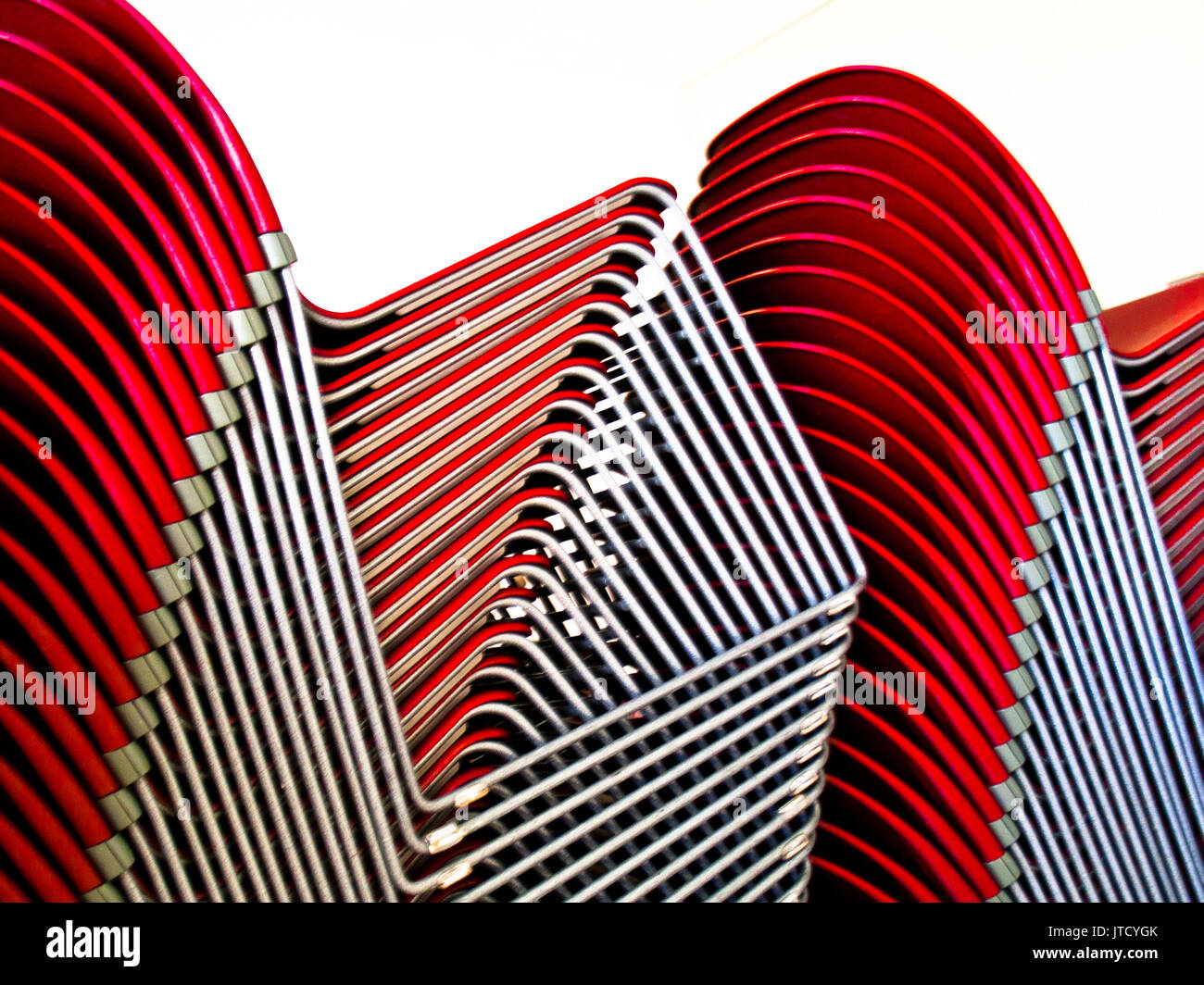 Red plastic and gray metal chairs form abstract shapes and patterns ...