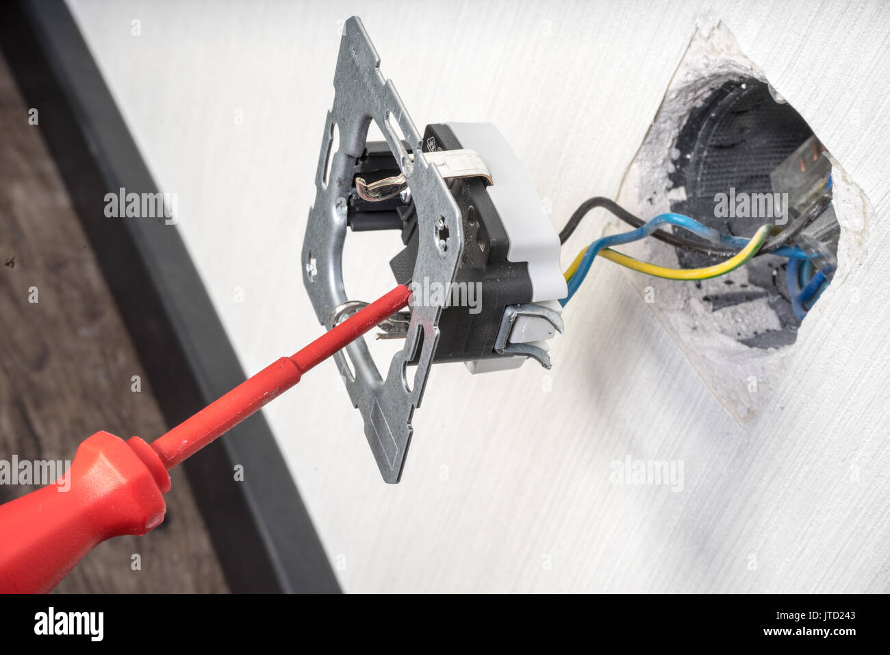 Electrician a wall socket with electronic multimeter Stock Photo